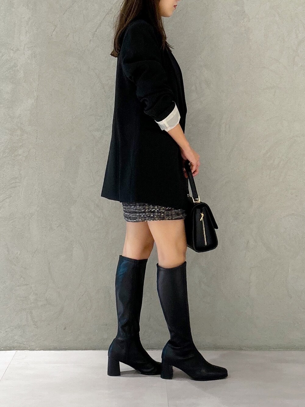 ブラック系のスカート、ブラック系のブーツ、ブラック系のショルダーバッグを着用したレディースの秋コーディネートの4枚目の写真