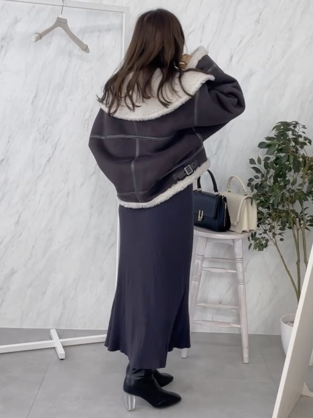 グレー系のワンピース、ブラック系のムートンコートを着用したレディースの秋コーディネートの3枚目の写真