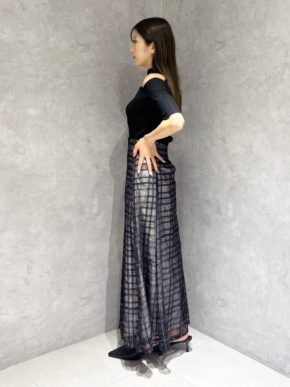 ブルー系のスカート、ブラック系のパンプス、ブラック系のニット/セーターを着用したレディースの春コーディネートの5枚目の写真