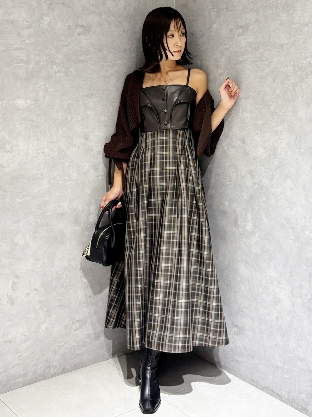 ブラウン系のワンピース、ブラック系のブーツ、ブラック系のハンドバッグを着用したレディースの秋コーディネートの7枚目の写真