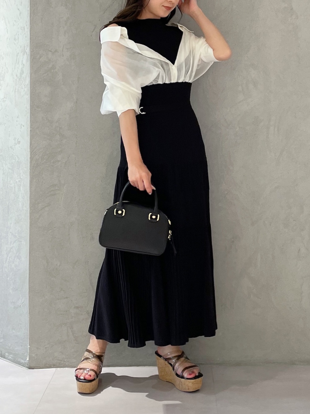 ブラック系のワンピース、ブラック系のサンダル、ホワイト系のボストンバッグを着用したレディースの春コーディネートの2枚目の写真