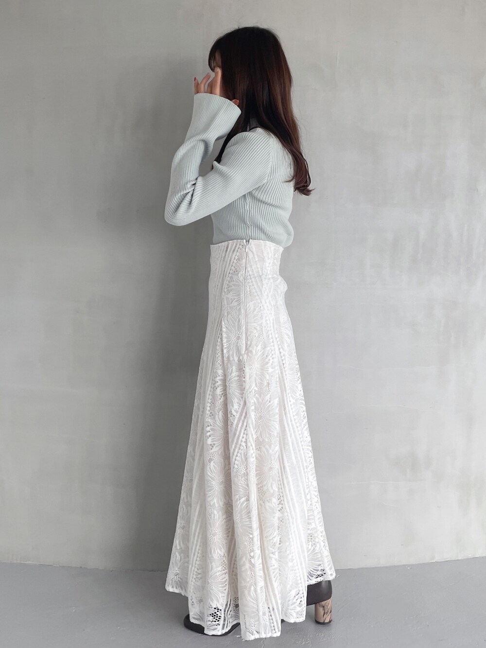 ホワイト系のスカート、グリーン系のニット/セーター、ブラウン系のブーツを着用したレディースの秋コーディネートの3枚目の写真