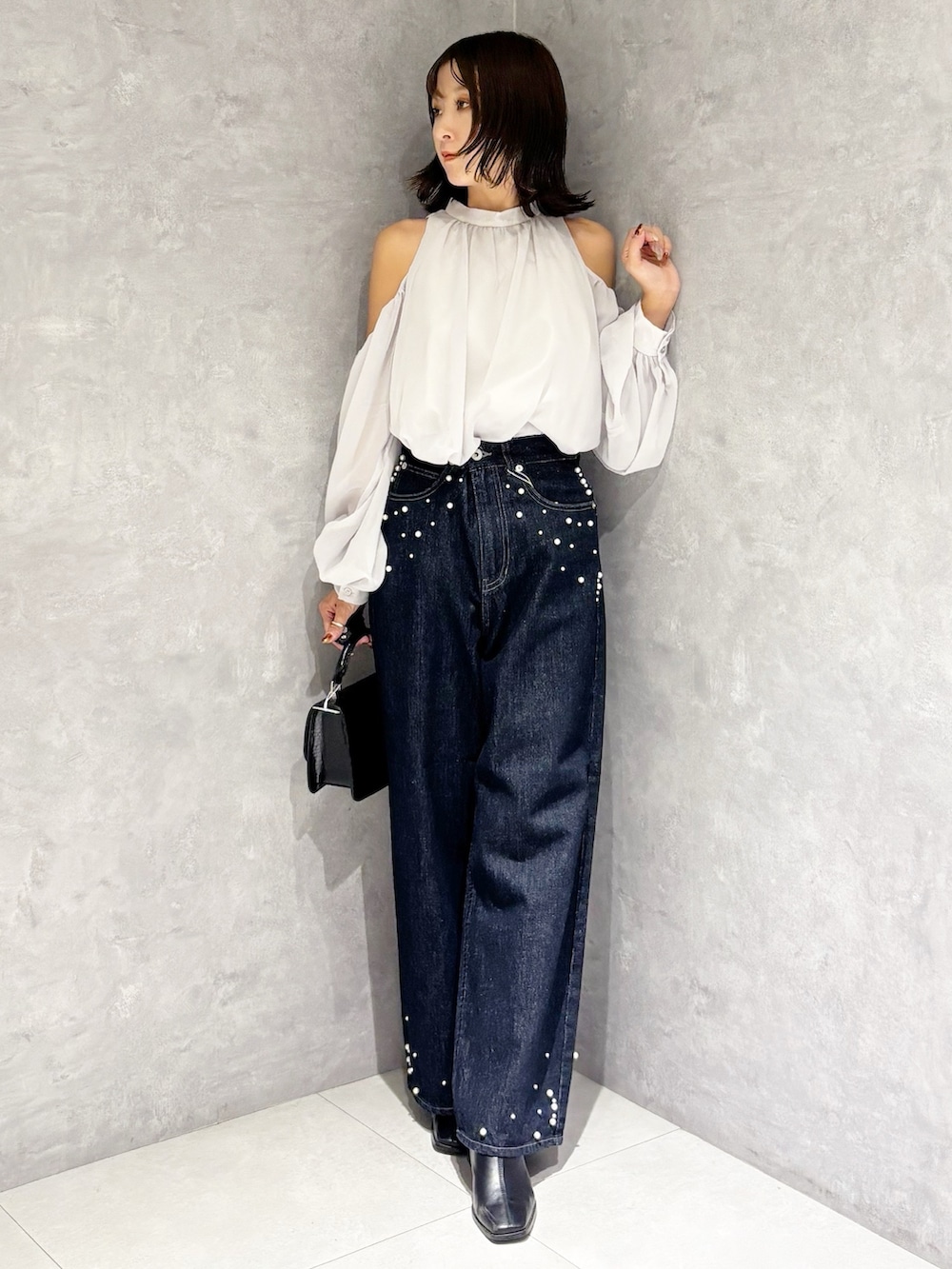 ブルー系のデニムパンツ、ブラック系のブーツ、ブラック系のハンドバッグを着用したレディースの秋コーディネートの5枚目の写真