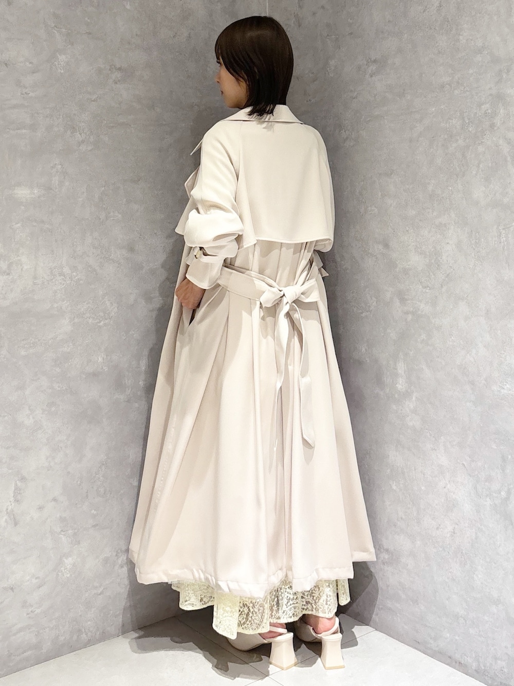 イエロー系のワンピース、ホワイト系のパンプス、ブラウン系のハンドバッグを着用したレディースの春コーディネートの3枚目の写真