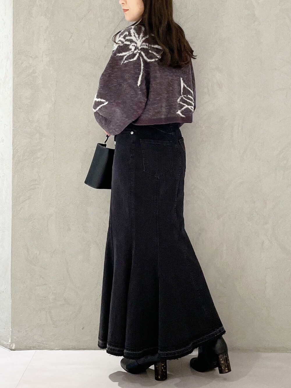 ブラック系のハンドバッグ、ブラック系のスカート、グレー系のニット/セーターを着用したレディースの秋コーディネートの3枚目の写真