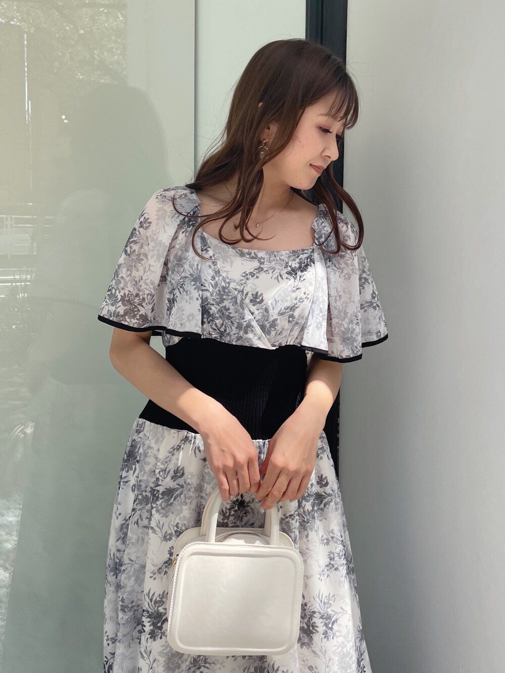 ブラック系のサンダル、ホワイト系のハンドバッグ、ホワイト系のワンピースを着用したレディースの春コーディネートの7枚目の写真