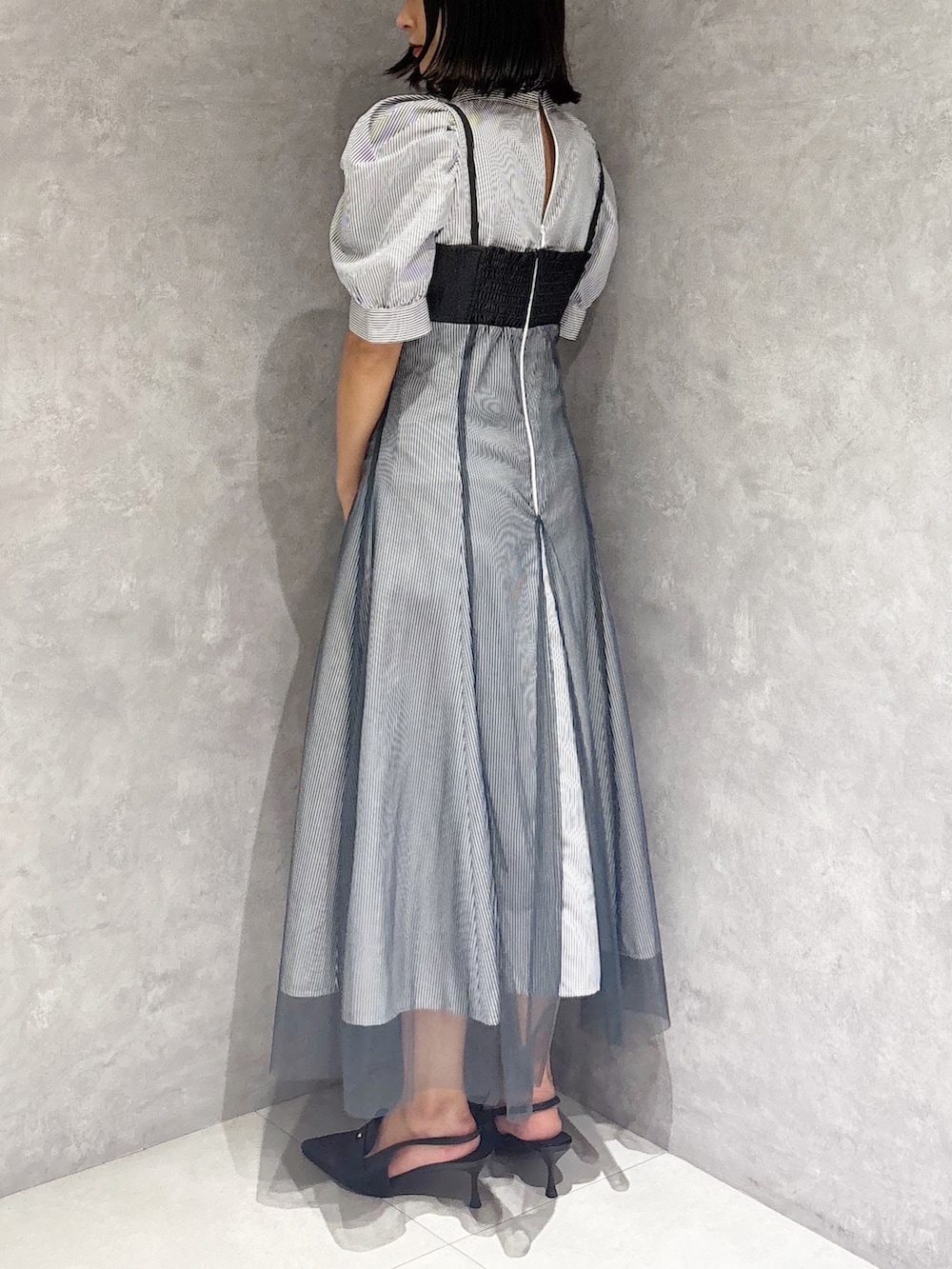 ブラック系のパンプス、ホワイト系のハンドバッグ、ブルー系のワンピースを着用したレディースの秋コーディネートの3枚目の写真