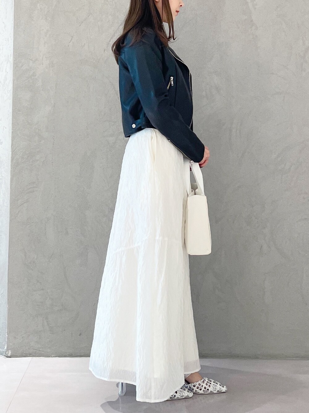 シルバー系のパンプス、ホワイト系のトートバッグ、ブラック系のライダースジャケットを着用したレディースの春コーディネートの3枚目の写真