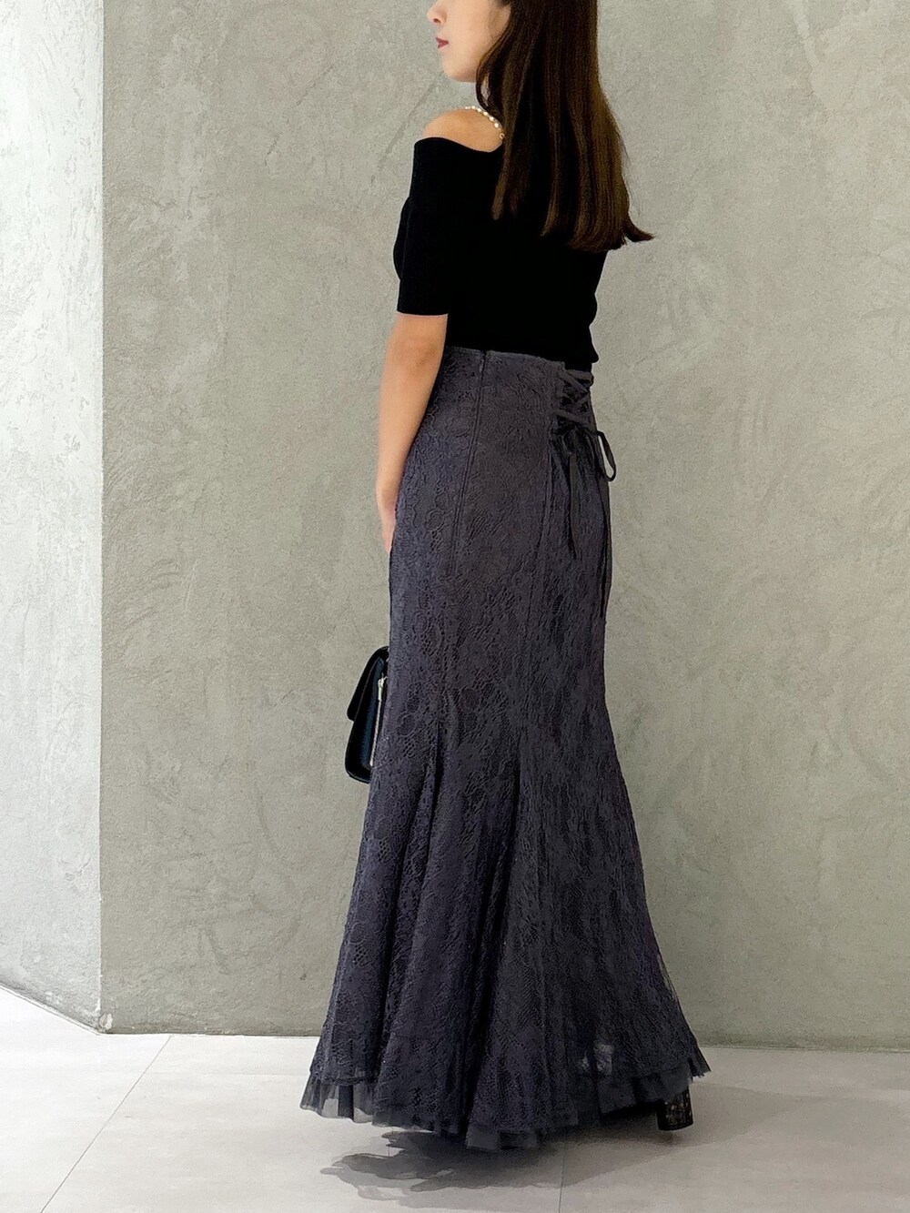 グレー系のスカート、ブラック系のブーツ、ブラック系のショルダーバッグを着用したレディースの秋コーディネートの3枚目の写真