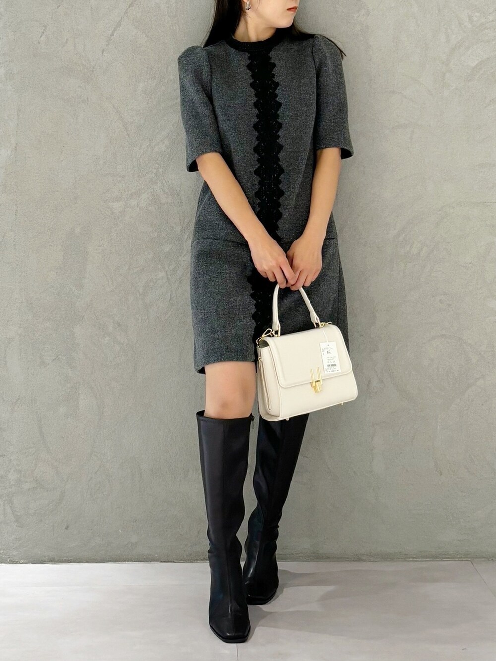 ブラック系のブーツ、ホワイト系のショルダーバッグ、グレー系のワンピースを着用したレディースの秋コーディネートの6枚目の写真