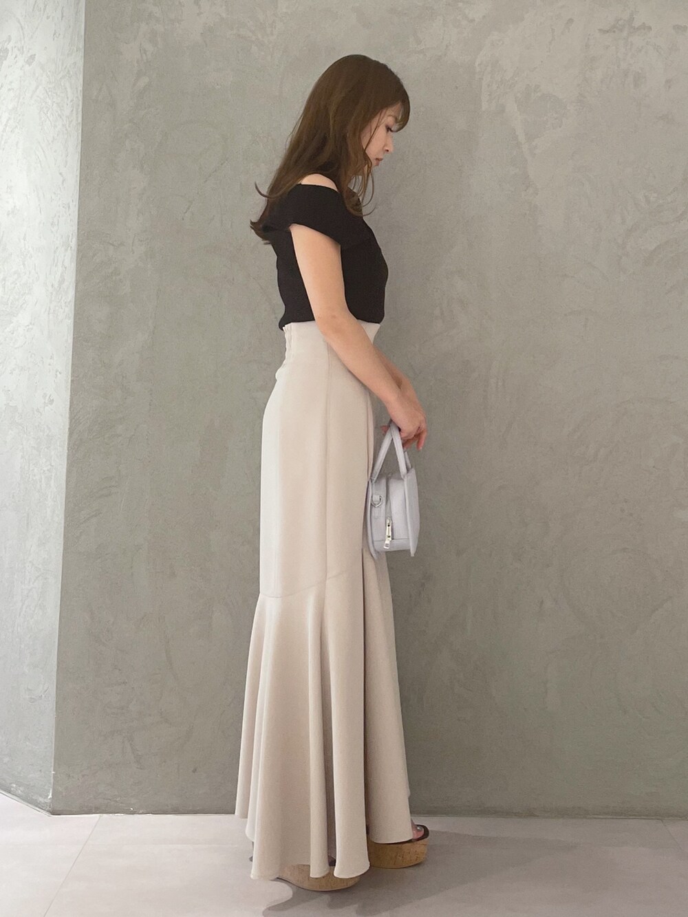 ブルー系のハンドバッグ、ブラック系のサンダル、ベージュ系のスカートを着用したレディースの春コーディネートの5枚目の写真