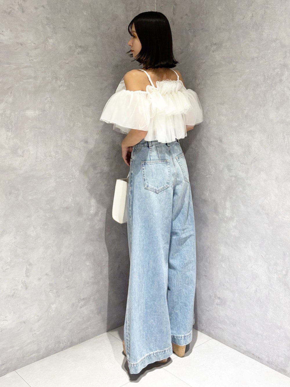 ブルー系のデニムパンツ、ブラウン系のサンダル、ホワイト系のトートバッグを着用したレディースの春コーディネートの4枚目の写真