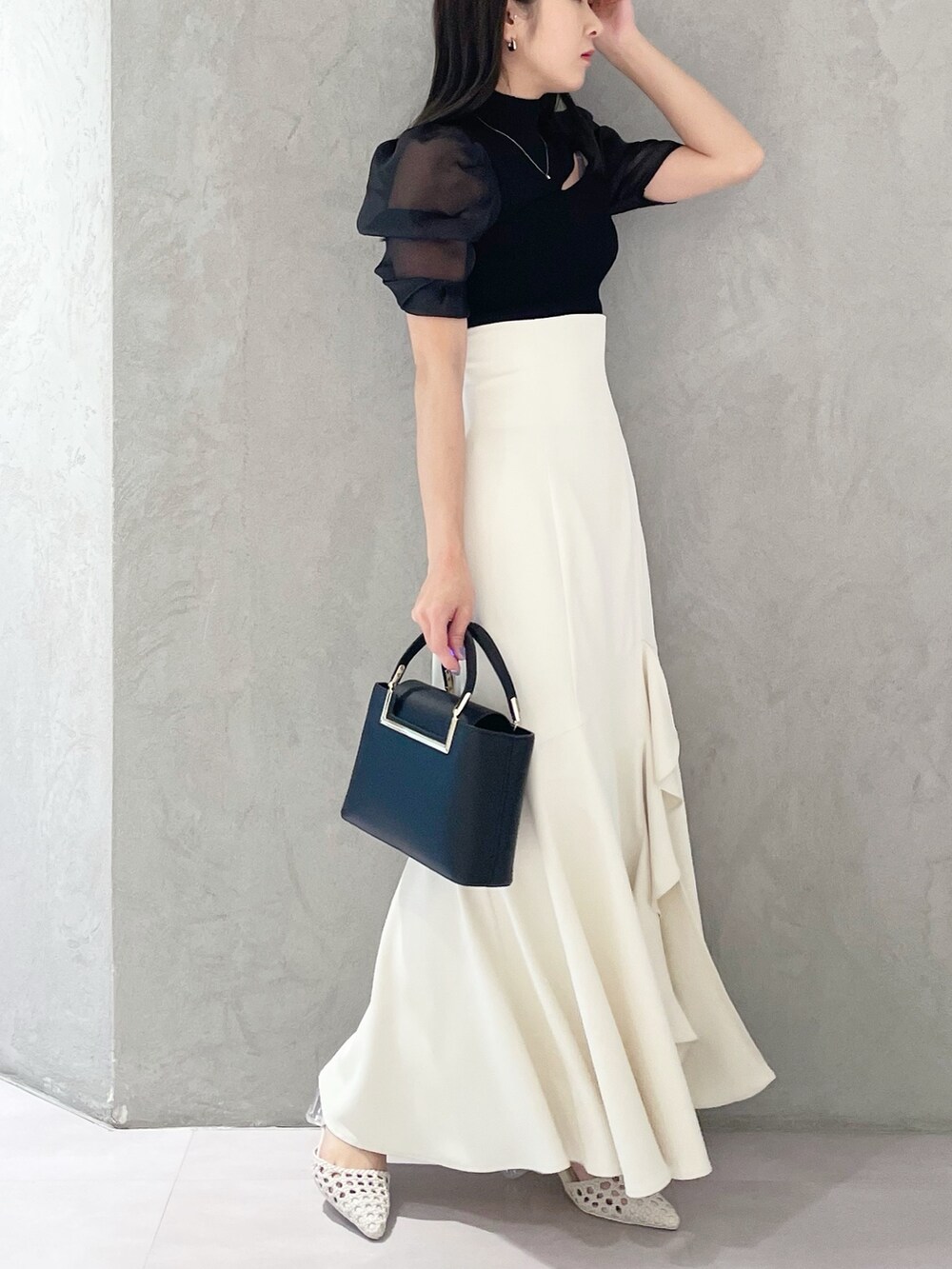 ホワイト系のパンプス、ブラック系のハンドバッグ、ブラック系のニット/セーターを着用したレディースの春コーディネートの5枚目の写真