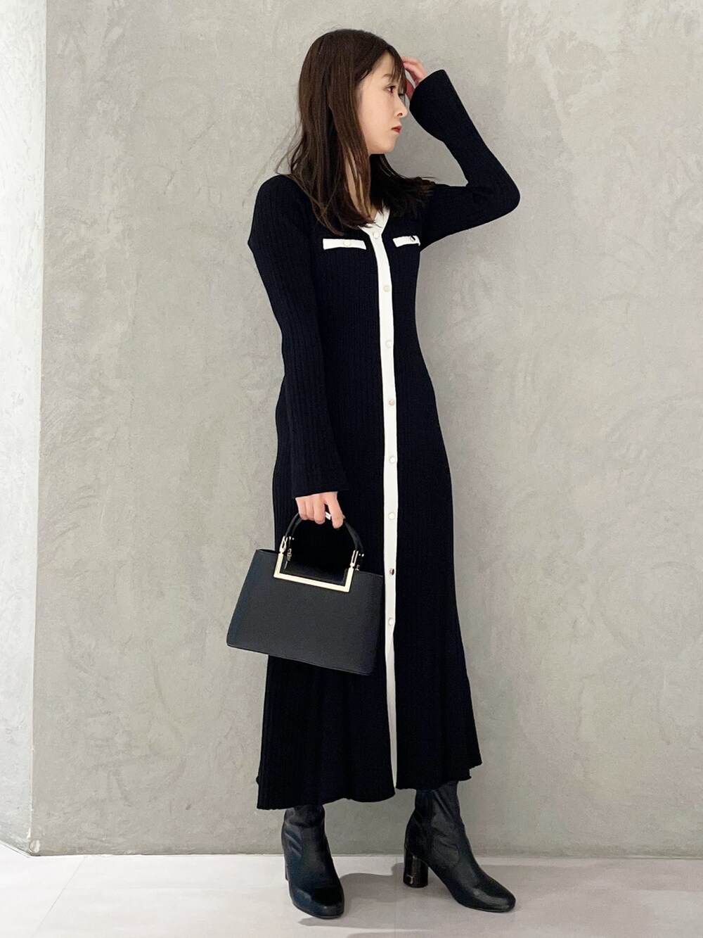 ブラック系のハンドバッグ、ブラック系のブーツ、ブラック系のワンピースを着用したレディースの冬コーディネートの2枚目の写真