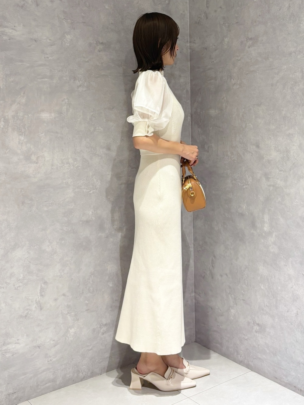ホワイト系のワンピース、ホワイト系のパンプス、ブラウン系のハンドバッグを着用したレディースの春コーディネートの4枚目の写真