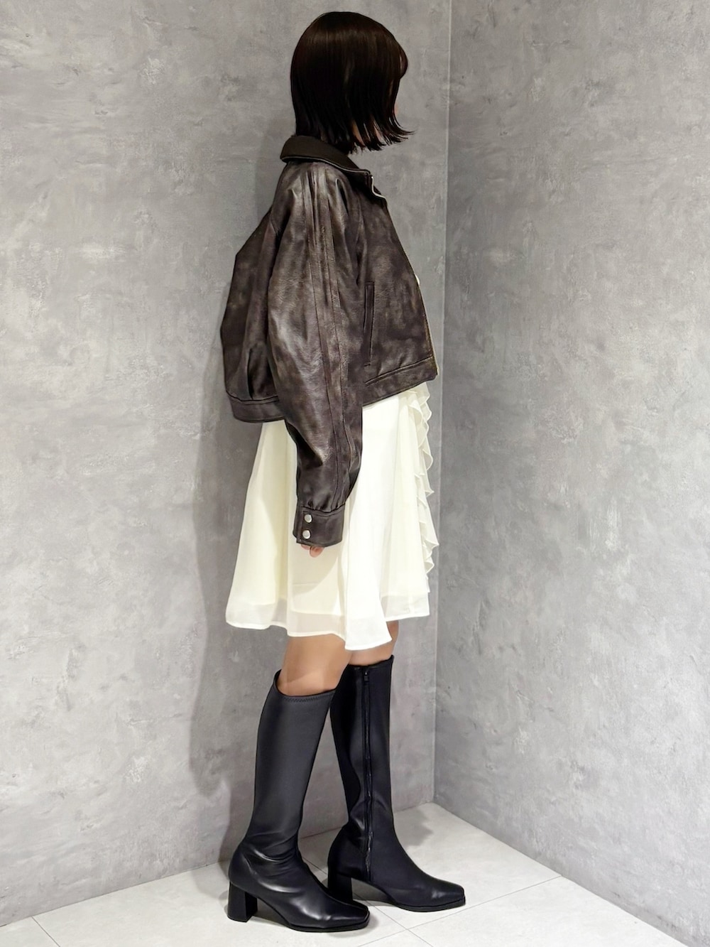 ブラック系のブーツ、ブラウン系のブルゾン、ホワイト系のワンピースを着用したレディースの秋コーディネートの2枚目の写真