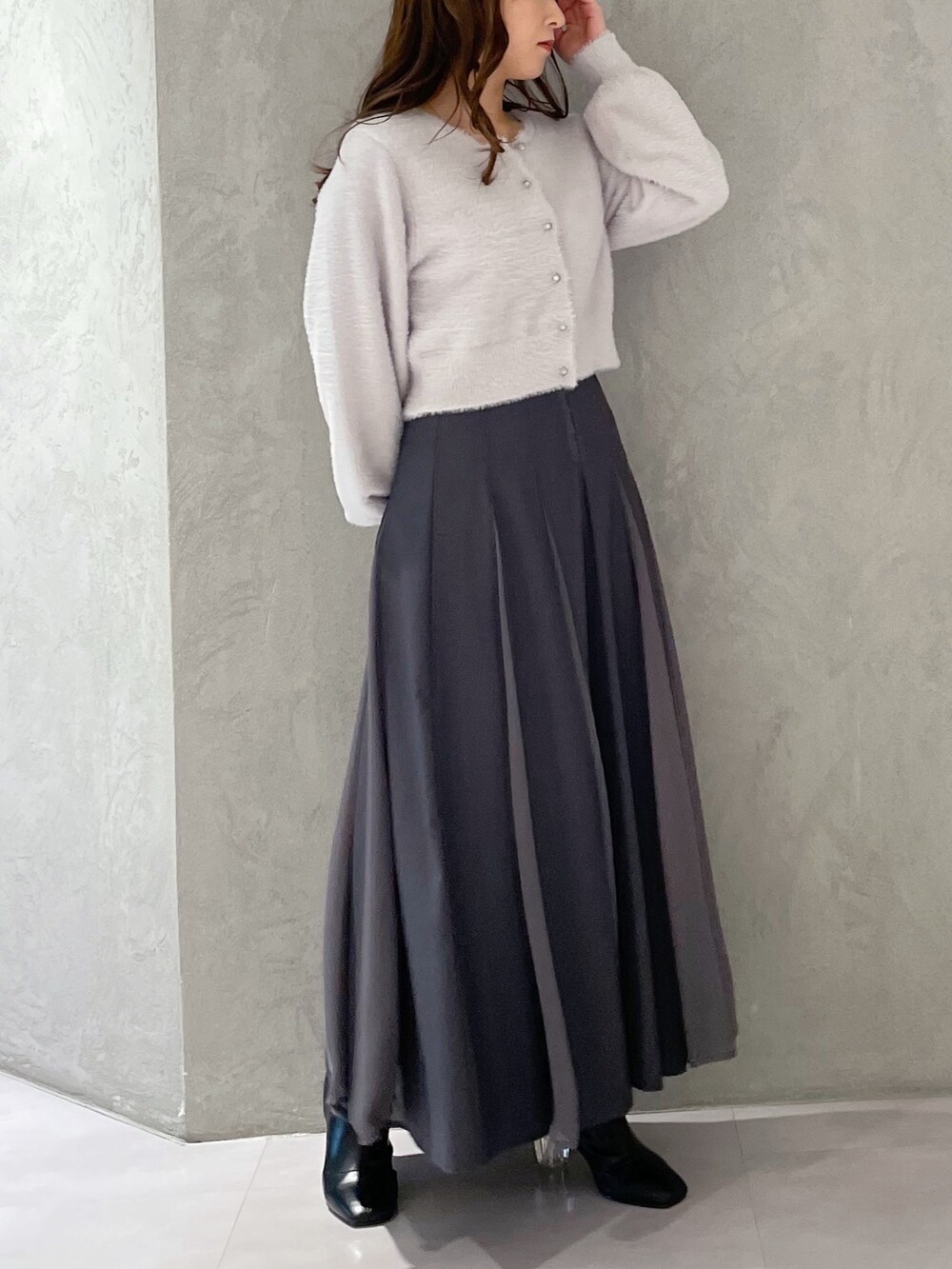 グレー系のカーディガン/ボレロ、グレー系のスカート、ブラック系のブーツを着用したレディースの冬コーディネートの2枚目の写真