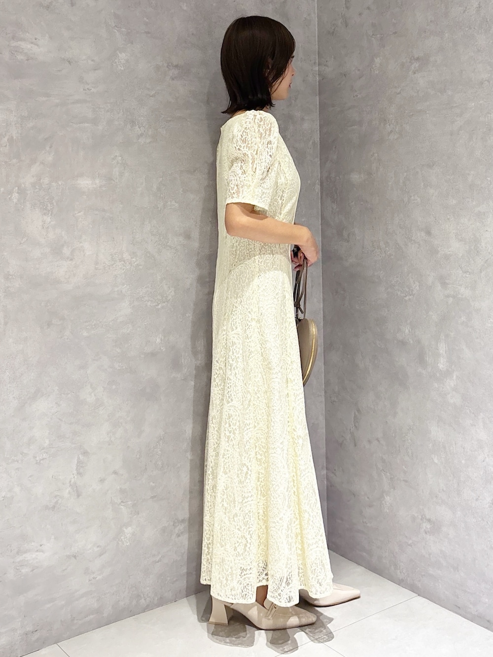 イエロー系のワンピース、ホワイト系のパンプスを着用したレディースの春コーディネートの2枚目の写真