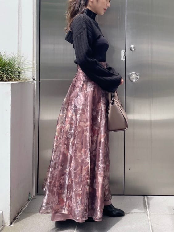 ブラウン系のスカート、ブラック系のニット/セーター、ブラック系のブーツを着用したレディースの秋コーディネートの3枚目の写真