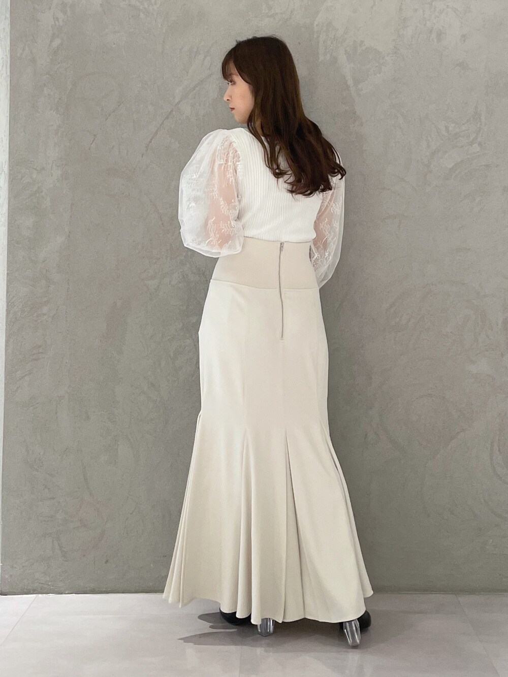 ホワイト系のスカート、ホワイト系のカーディガン/ボレロ、ブラック系のブーツを着用したレディースの冬コーディネートの5枚目の写真