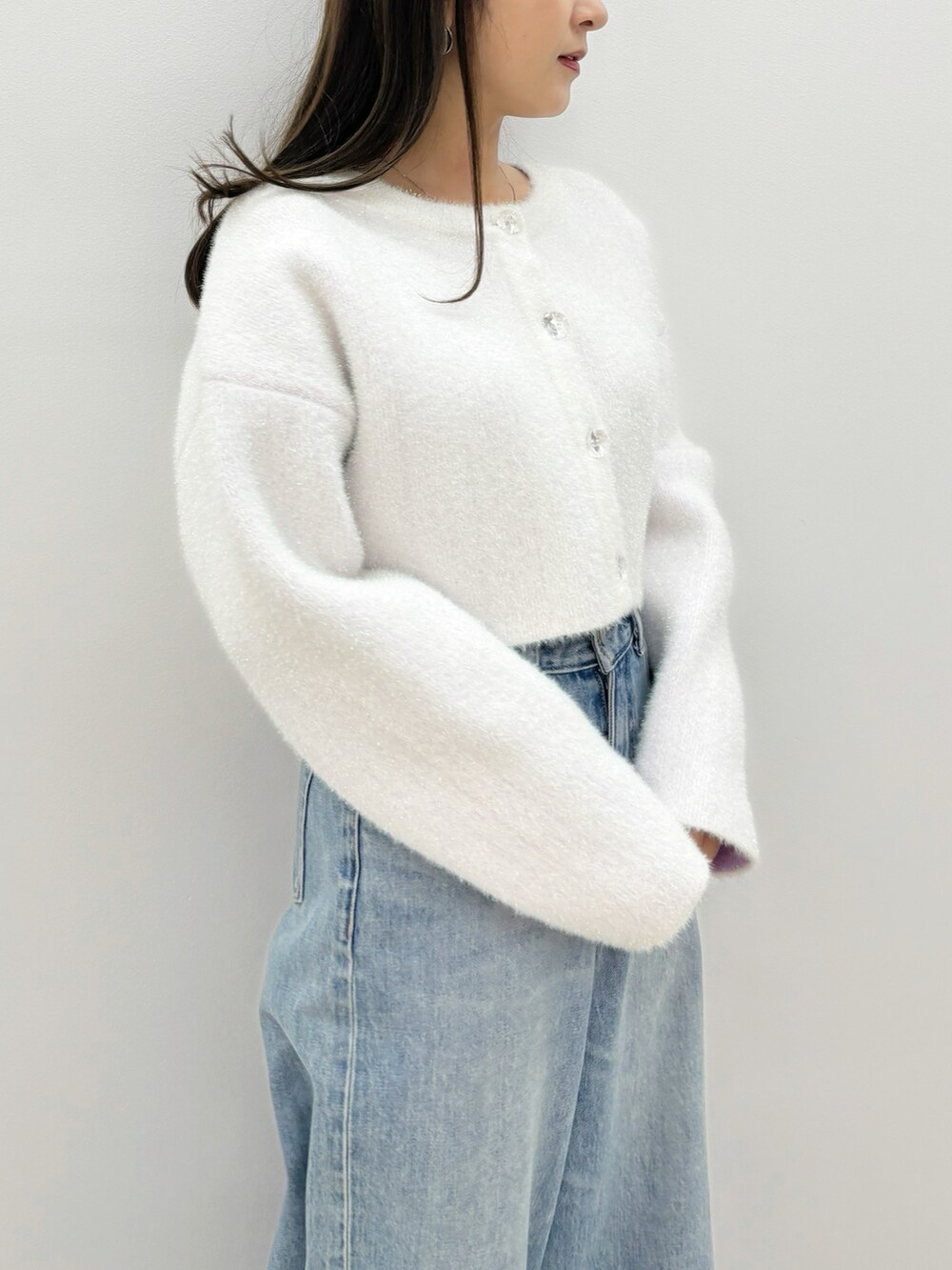 ブルー系のデニムパンツ、ブラック系のブーツ、ホワイト系のカーディガン/ボレロを着用したレディースの秋コーディネートの2枚目の写真