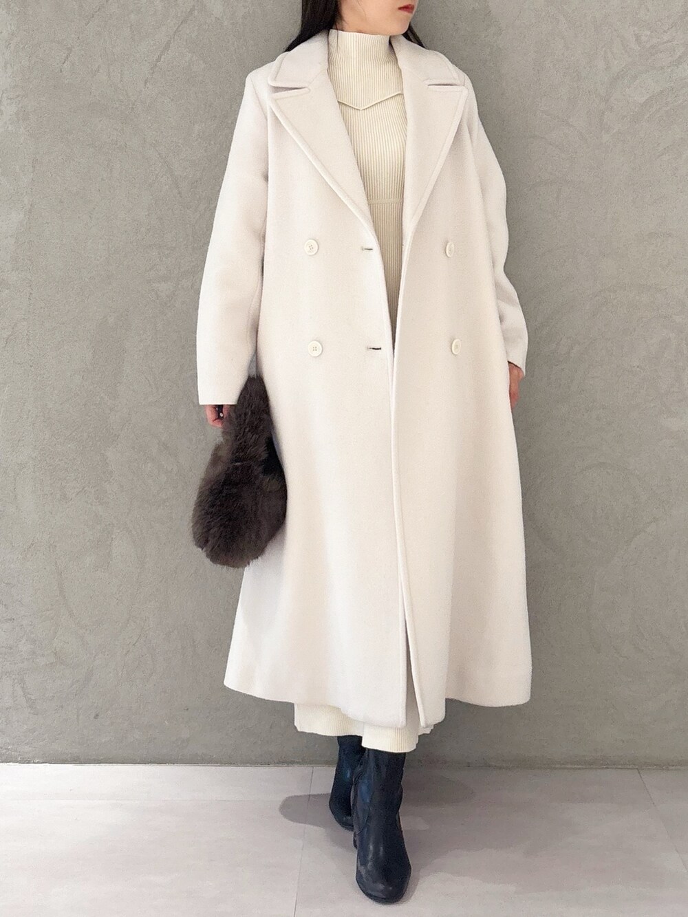 ホワイト系のチェスターコート、ブラック系のブーツ、ブラウン系のハンドバッグを着用したレディースの冬コーディネートの6枚目の写真