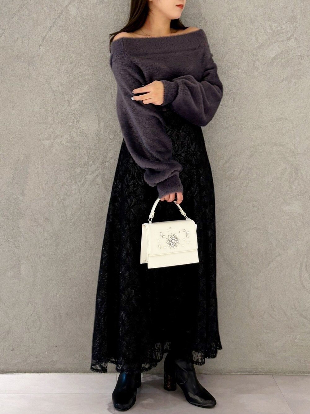 ブラック系のスカート、ブラック系のブーツ、ホワイト系のショルダーバッグを着用したレディースの冬コーディネートの5枚目の写真