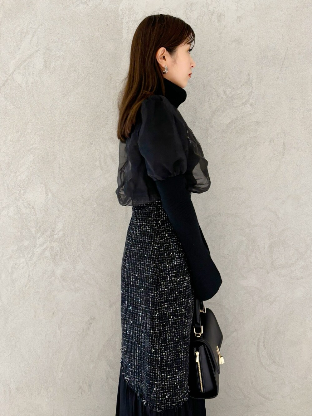 ブラック系のスカート、ブラック系のショルダーバッグ、ブラック系のブーツを着用したレディースの秋コーディネートの3枚目の写真