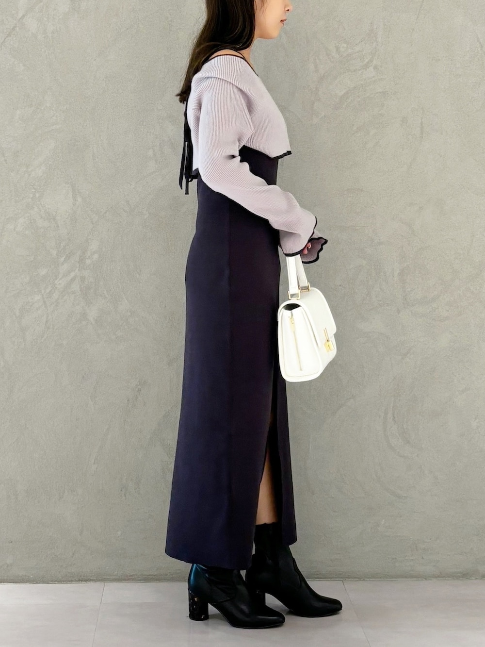 グレー系のワンピース、ブラック系のブーツ、ホワイト系のハンドバッグを着用したレディースの秋コーディネートの3枚目の写真