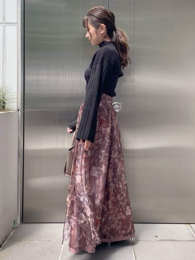 ブラウン系のスカート、ブラック系のニット/セーター、ブラック系のブーツを着用したレディースの秋コーディネートの2枚目の写真