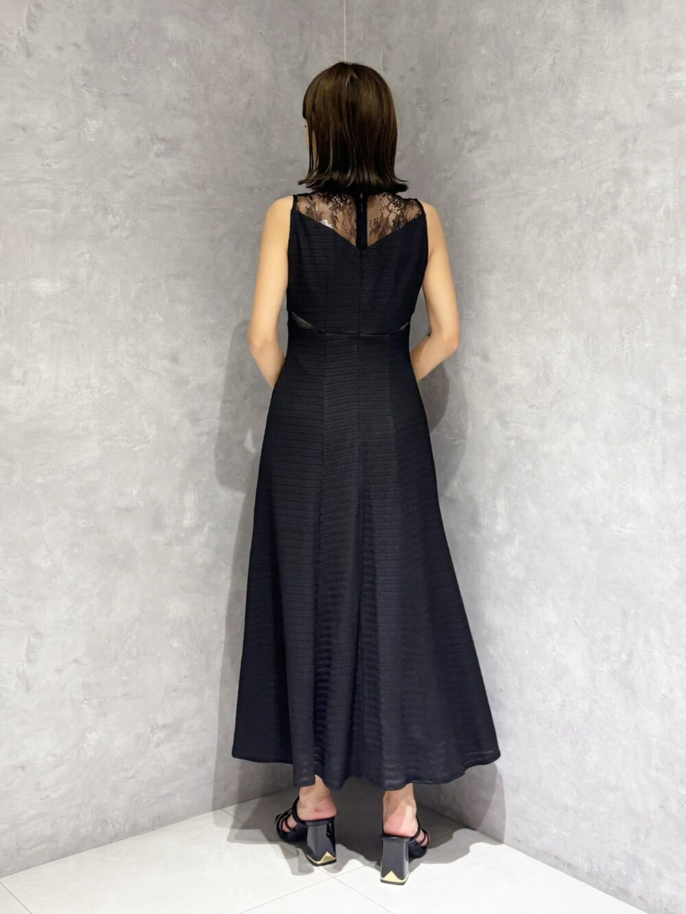 ブラック系のワンピース、ホワイト系のハンドバッグ、ブラック系のサンダルを着用したレディースの夏コーディネートの3枚目の写真