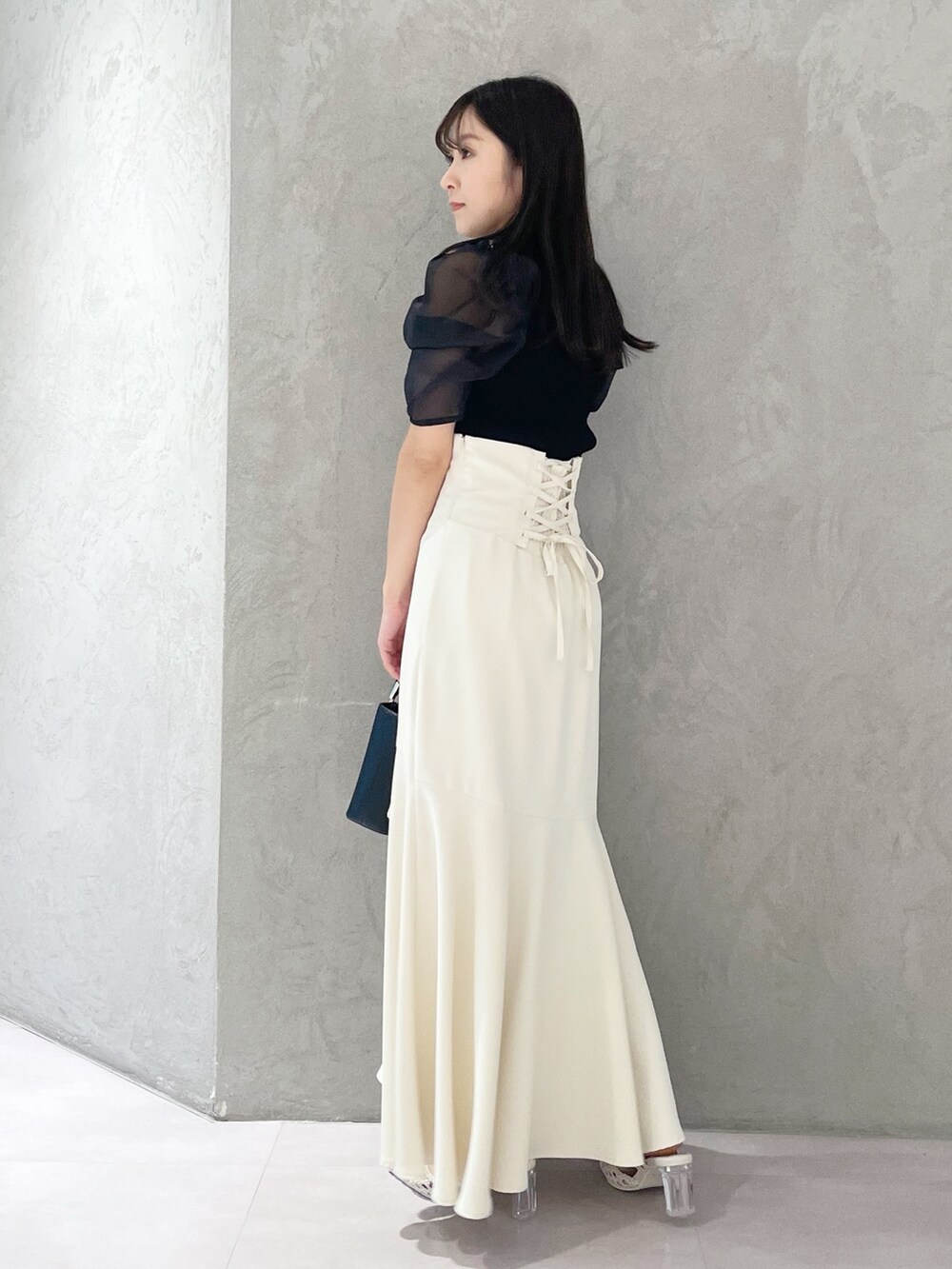 ホワイト系のパンプス、ブラック系のハンドバッグ、ブラック系のニット/セーターを着用したレディースの春コーディネートの6枚目の写真