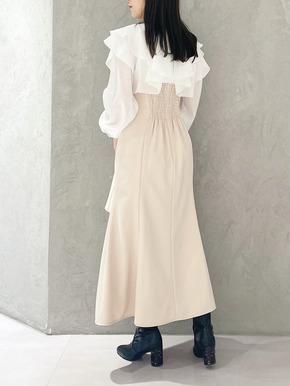 ベージュ系のワンピース、ホワイト系のハンドバッグ、ブラック系のブーツを着用したレディースの冬コーディネートの3枚目の写真