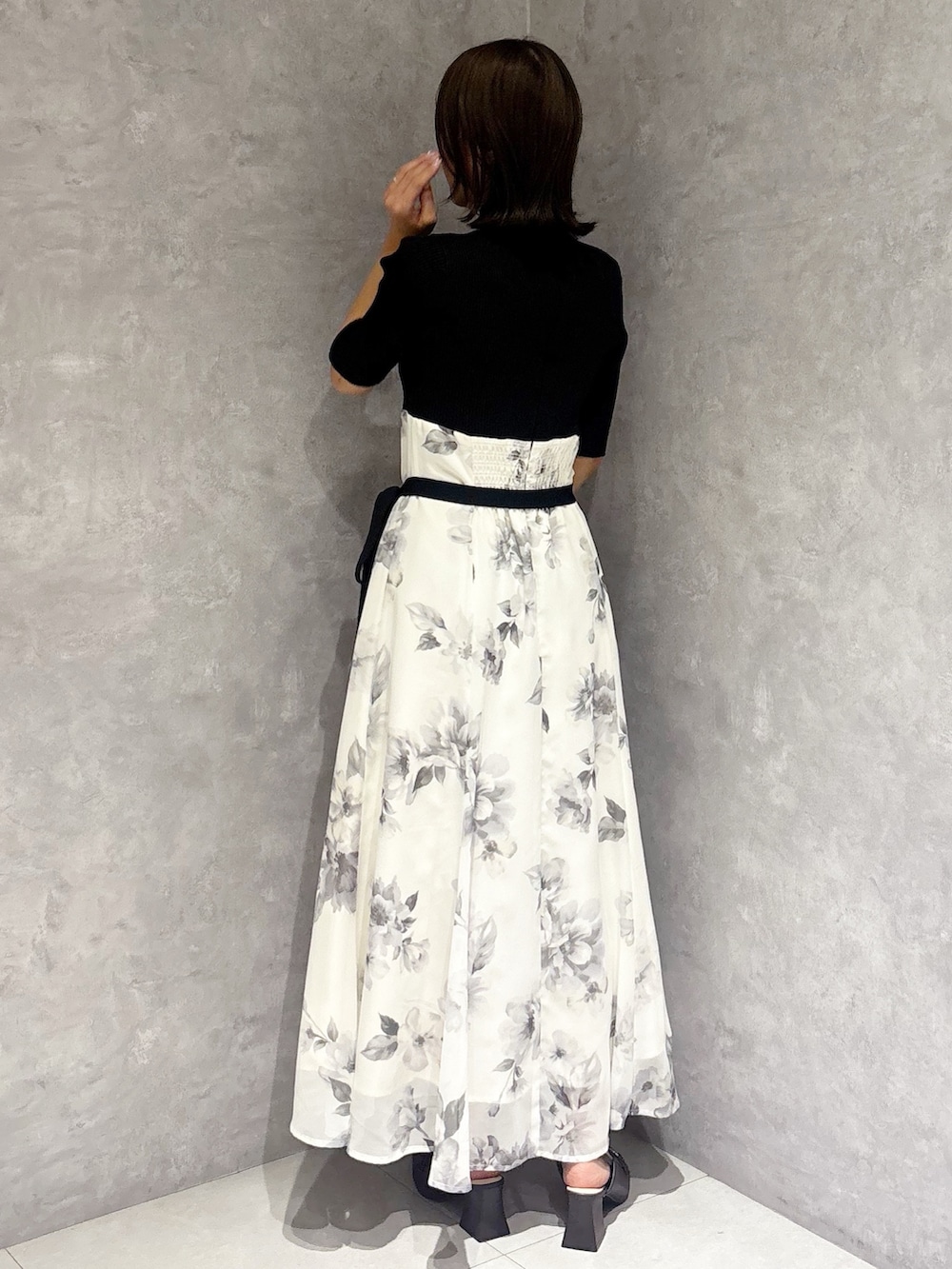 ブラック系のワンピース、ブラウン系のパンプス、ホワイト系のハンドバッグを着用したレディースの春コーディネートの3枚目の写真