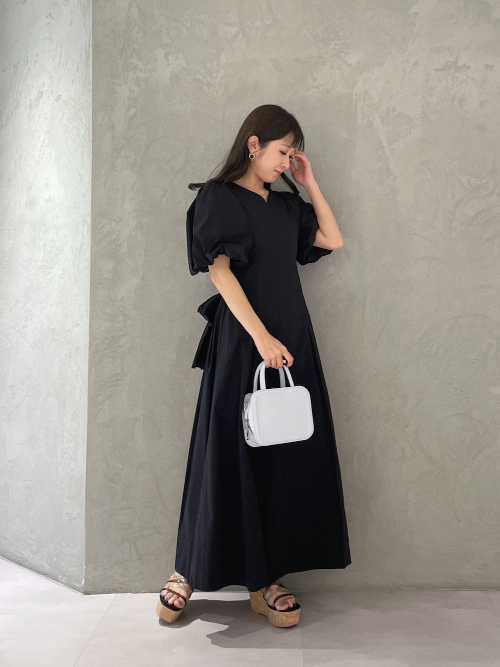 ブラック系のサンダル、ブルー系のハンドバッグ、ブラック系のワンピースを着用したレディースの春コーディネートの2枚目の写真