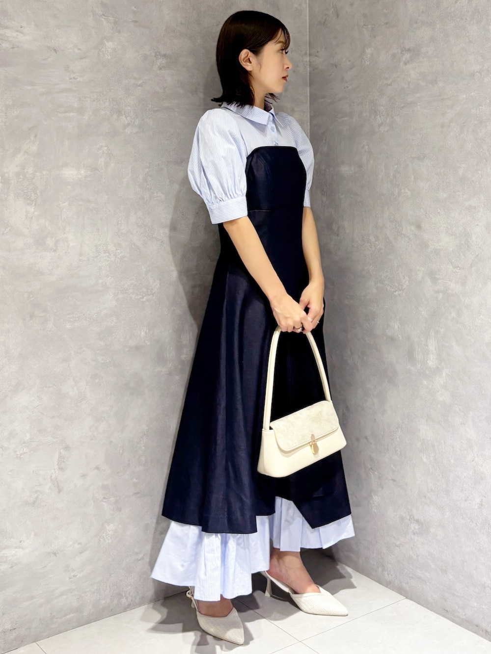 ブルー系のワンピース、ホワイト系のパンプス、ホワイト系のハンドバッグを着用したレディースの春コーディネートの2枚目の写真