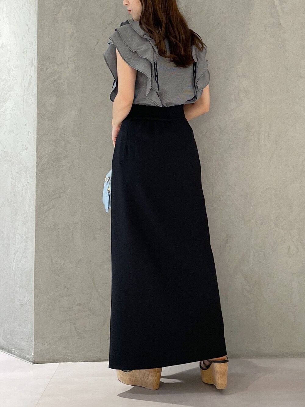 ブラック系のスカート、ブラック系のサンダル、ブルー系のボストンバッグを着用したレディースの春コーディネートの5枚目の写真