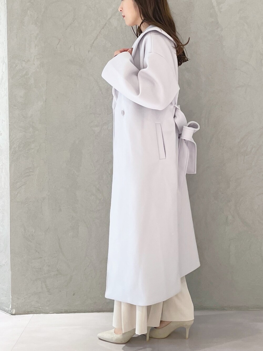 ホワイト系のハンドバッグ、ホワイト系のパンプス、ブルー系のニット/セーターを着用したレディースの秋コーディネートの2枚目の写真