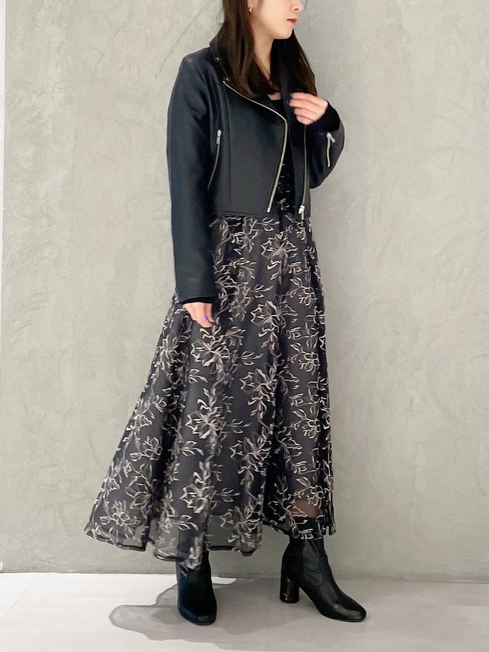 グレー系のスカート、ブラック系のライダースジャケット、ブラック系のブーツを着用したレディースの冬コーディネートの3枚目の写真