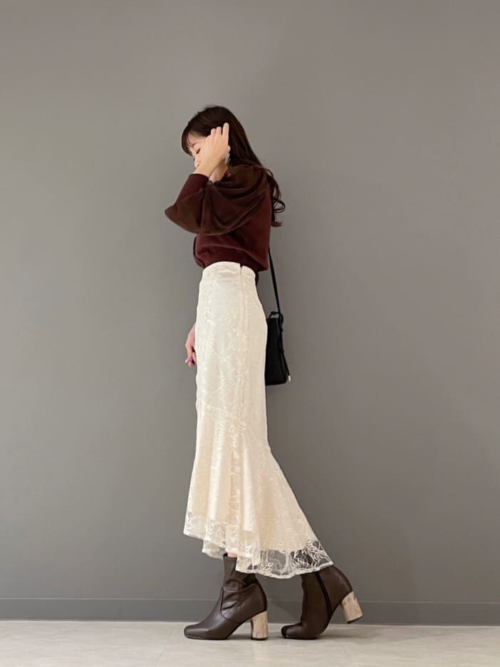 ベージュ系のショルダーバッグ、ブラウン系のカーディガン/ボレロ、ホワイト系のスカートを着用したレディースの冬コーディネートの5枚目の写真