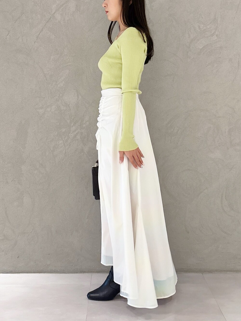 ホワイト系のスカート、ブラック系のブーツ、ブラウン系のハンドバッグを着用したレディースの冬コーディネートの2枚目の写真