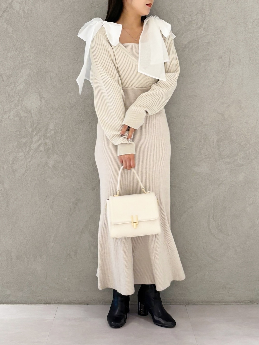 ホワイト系のハンドバッグ、ブラック系のブーツ、ホワイト系のワンピースを着用したレディースの冬コーディネートの5枚目の写真