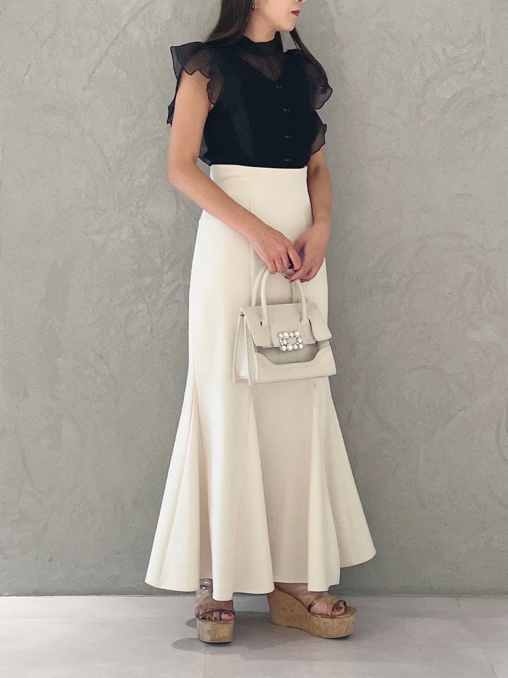 ブラック系のニット/セーター、ホワイト系のスカート、ブラウン系のサンダルを着用したレディースの夏コーディネートの6枚目の写真