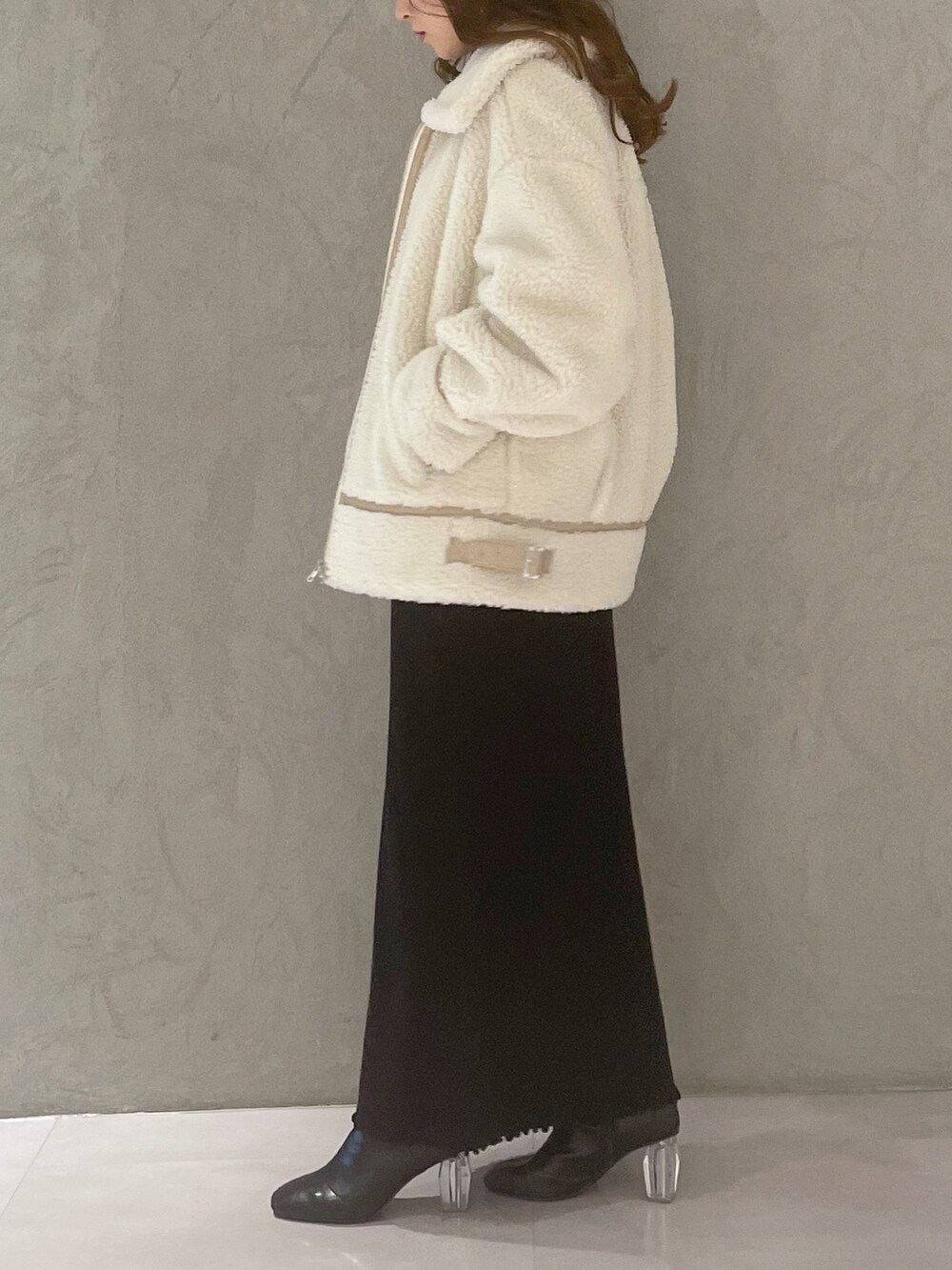 ブラック系のワンピース、ホワイト系のその他アウター、ブラック系のブーツを着用したレディースの冬コーディネートの3枚目の写真