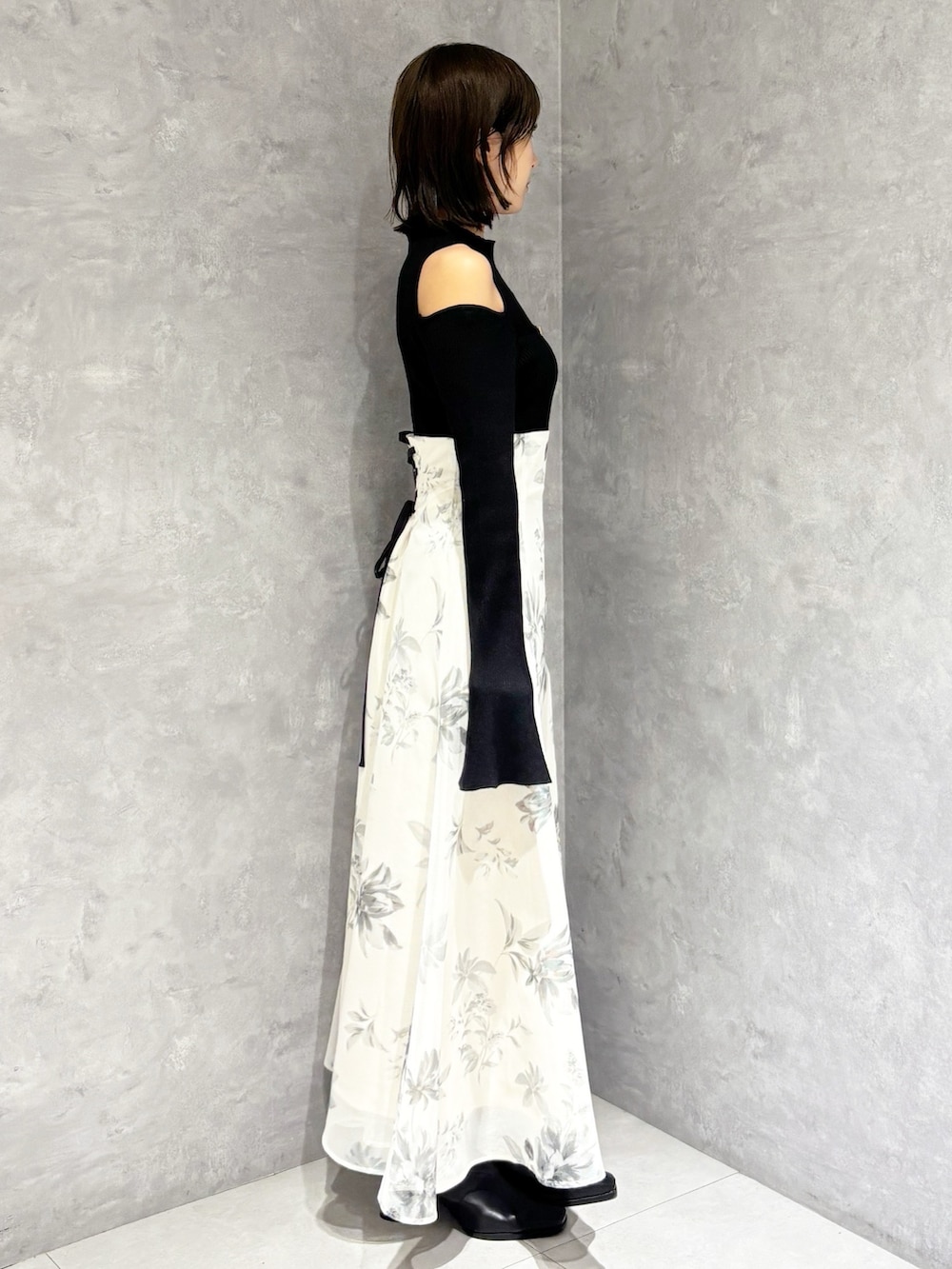 ホワイト系のスカート、ブラック系のニット/セーター、ブラック系のブーツを着用したレディースの冬コーディネートの2枚目の写真