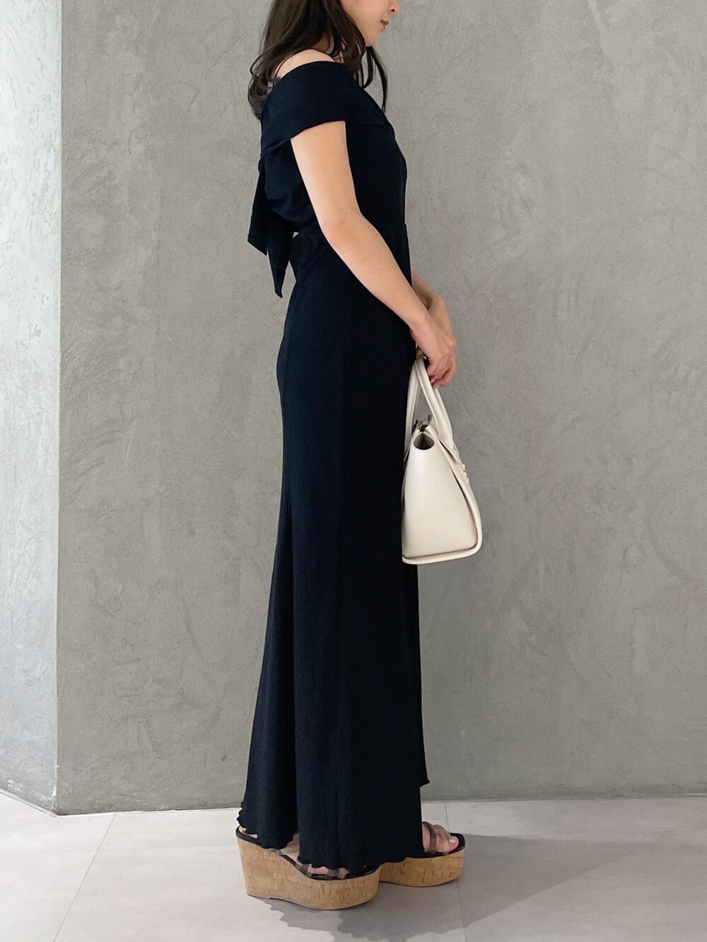 ホワイト系のトートバッグ、ブラック系のサンダル、ブラック系のワンピースを着用したレディースの夏コーディネートの3枚目の写真