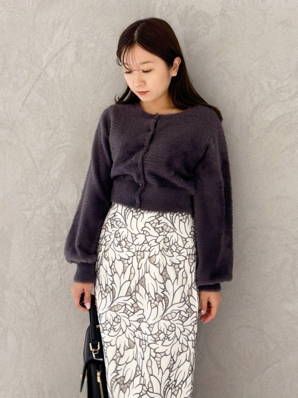 ホワイト系のスカート、ブラック系のブーツ、ブラック系のショルダーバッグを着用したレディースの冬コーディネートの2枚目の写真