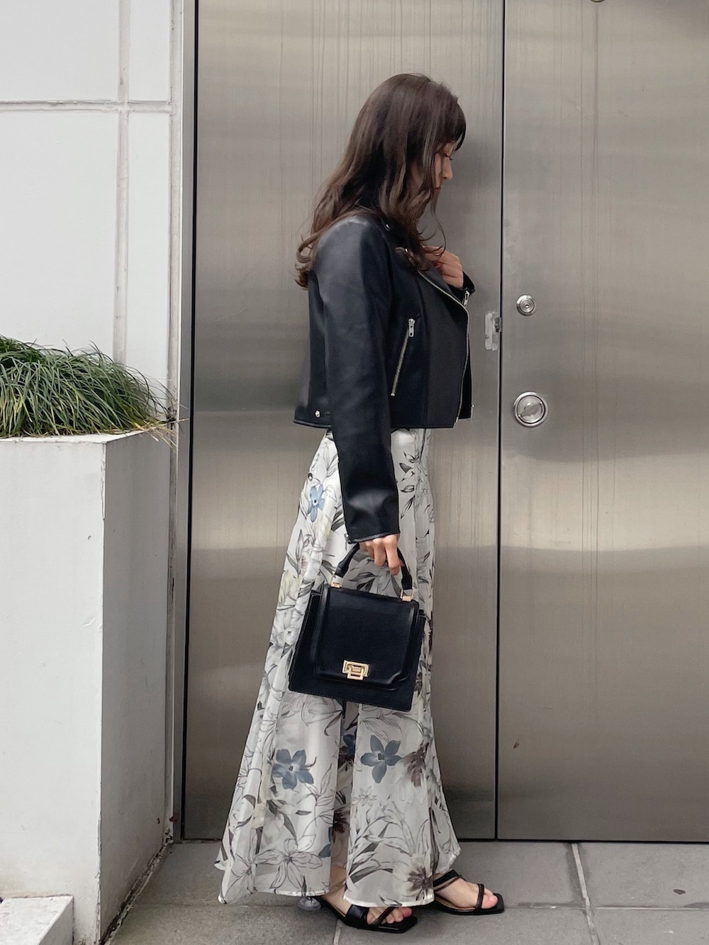 グリーン系のスカート、ブラック系のライダースジャケット、ブラック系のニット/セーターを着用したレディースの冬コーディネートの4枚目の写真