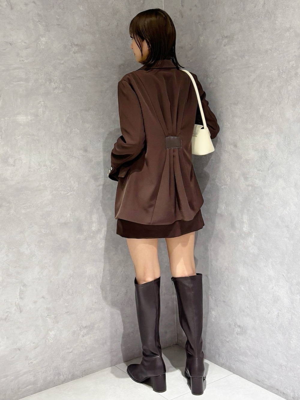 ホワイト系のシャツ/ブラウス、ホワイト系のハンドバッグ、ブラウン系のブーツを着用したレディースの春コーディネートの3枚目の写真