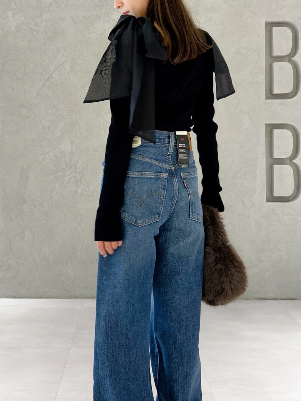 ブラウン系のハンドバッグ、シルバー系のパンプス、ブラック系のニット/セーターを着用したレディースの秋コーディネートの2枚目の写真